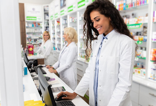 Young Female Pharmacist Working At Pharmacy Behind The Counter.