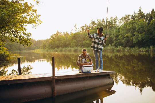 Portrait of young couple fishing on warm summer day in countryside at sunset. Romantic day