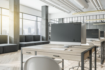 Close up of desktop with empty computer screen in modern coworking designer office interior with wooden flooring and couch. Mock up, 3D Rendering.