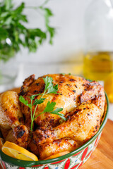 Whole roasted chicken with fresh parsley and lemon wedges in a festive dish