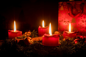Decorated advent wreath made of fir branches with burning red candles