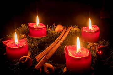 Decorated advent wreath made of fir branches with burning red candles