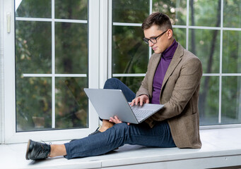 Freelancer copywriter using laptop computer outside. Portrait of handsome man working on project....