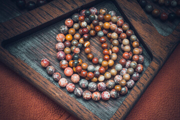 a lot of different beads made of natural semi-precious stones in the cell of a decorative wooden...