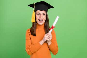 Portrait of attractive cheerful girl wearing master's hat holding scroll paper bachelor degree...