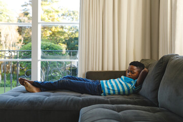 African american boy with eyes closed lying on couch resting by window in living room © WavebreakMediaMicro