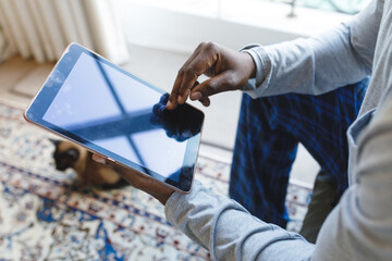 African american man using tablet and sitting on couch in living room