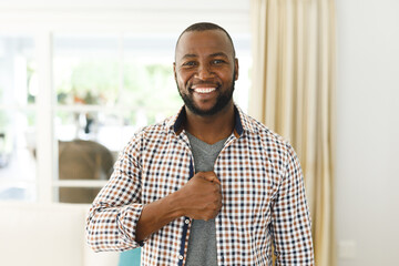 Portrait of african american man smiling and looking at camera in living room talking sign language
