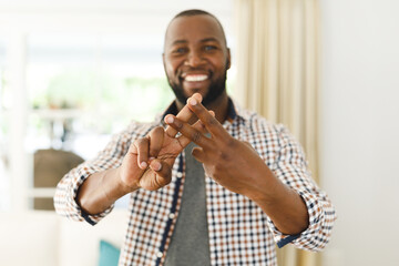 Portrait of african american man smiling and looking at camera in living room talking sign language
