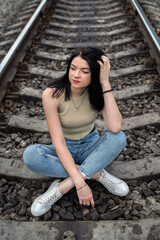 pretty young woman is standing near the railway tracks