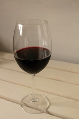 Crystal goblet containing red wine on a neutral white background. Available space to write.