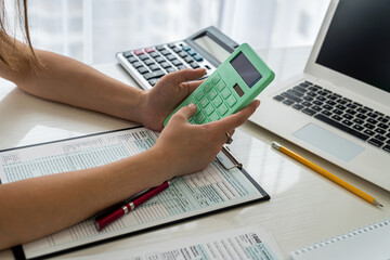 Female hands with calculator above 1040 tax form close up