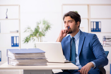Naklejka premium Young male employee and too much work in the office