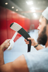 Preparing the hockey stick for play - wrapping tape around the handle and hook for protection and better grip on hands and puck - obrazy, fototapety, plakaty
