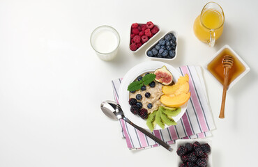 milk, plate with oatmeal porridge and fruit, freshly squeezed juice in a transparent glass...