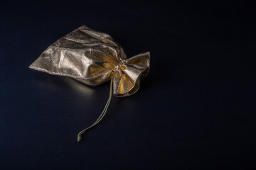 Woven bags of gold color tied with gold thread, holiday gift on a dark background