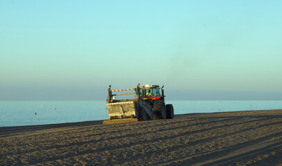 Fototapeta premium A tractor moving the sand on the beach