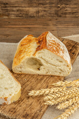 Freshly baked bread with wheat ears, fragrant pieces on a cutting board