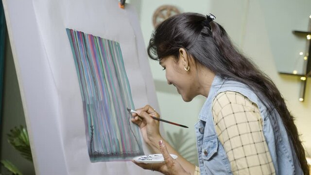 Young Indian girl or female artist doing painting on canvas- concept of passion, hobby and leisure activities.