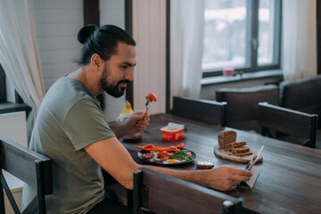 A man is having breakfast at home with a tablet.