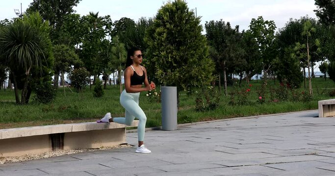 Young fit sporty black African woman in top and leggings does leaning forward exercise working out outdoor on summer. Sport, fitness training, active healthy lifestyle, stretching, warm up concept.