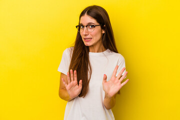 Young caucasian woman isolated on yellow background rejecting someone showing a gesture of disgust.