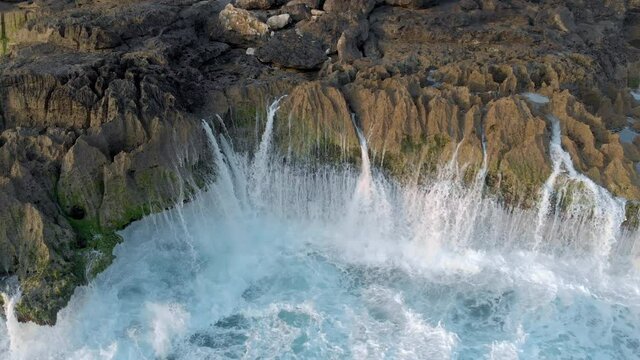 Axel Aerial view from drone of rock cliff on sea coastline. Out of this world beauty of rocky shore formed by splashing waves with lots of foam. Beautiful scenery of natural forces shot by drone.