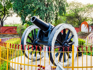 Close up shot steel cannon with wheels protected by steel fence.