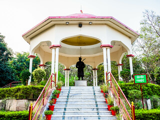 Front shot of historcial Sculpture with trees in the background in garden.