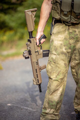 Close up of a man holding an airsoft assault rifle in military uniform