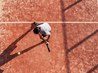 Overhead of a paddle tennis player who is hitting the ball on an outdoor court.