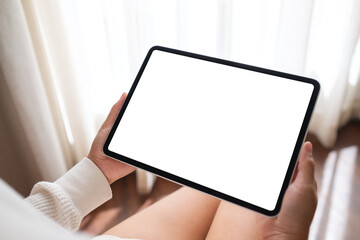 Mockup image of a woman holding digital tablet with blank desktop screen at home