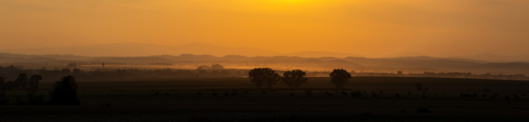 Fototapeta na wymiar Orange sunset over the fields. Good lighting conditions, distant planes visible