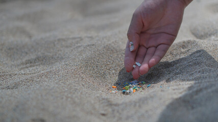 Side view of a hand holding microplastics on the right with copy space on the left. Non-recyclable materials. Selective focus of microplastics. Global warming and climate change concept. 