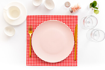 Tableware set with empty plate with dishware and glasses on napkin