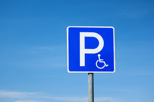 Disabled parking international road sign. Blue sky on background