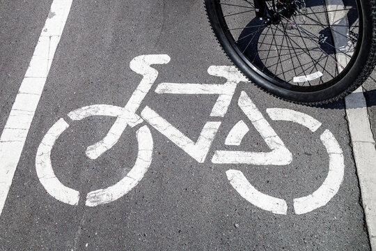 Bicycle symbol on designated track. There is cyclist little to side, wheel is visible