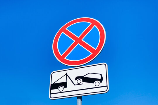 Combination of road signs 'No stopping' or 'No parking' and "Car evacuation". Blue sky on background