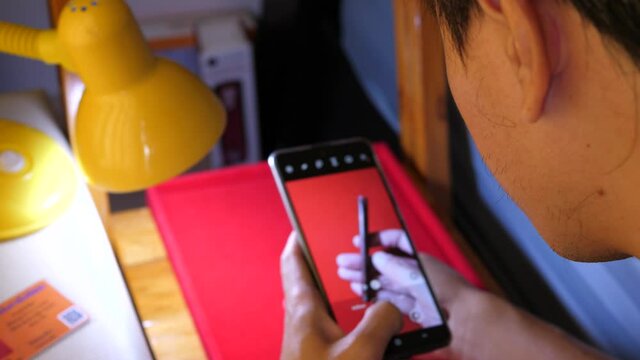 Asian man take photo small amulet product by mobile phone. Concept of amulet job, online business, new occupation, Thailand hobby lifestyle, vintage vs technology.