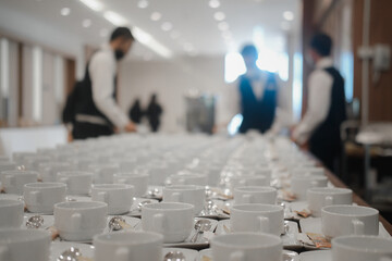 Waiter arranging white coffee cups for coffee break in meeting. Shallow focus