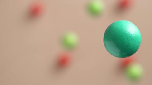 Green and red balls are moving on a pink background, 3D effect. Bright abstract background with spherical shapes.