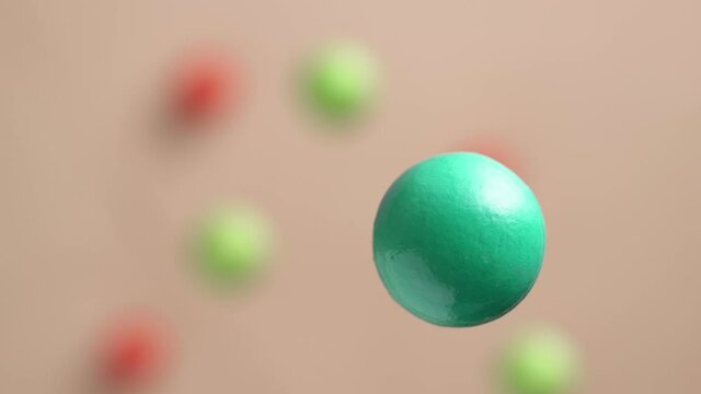 Green and red balls are moving on a pink background, 3D effect. Bright abstract background with spherical shapes.