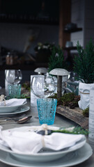 Set table with winter/christmas decoration in front of a kitchen, wineglass in focus