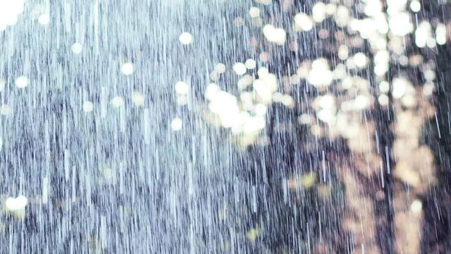 Downpour. Rainy drops in slow motion. Raindrops on the background of the sun.