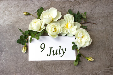 July 9th. Day 9 of month, Calendar date. White roses border on pastel grey background with calendar...