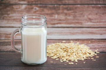 white milk drink in a mug and dry oat flakes