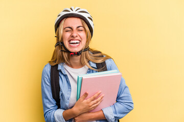 Young caucasian student woman wearing a bike helmet isolated on yellow background  laughing and having fun.