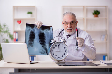Old male doctor in time management concept