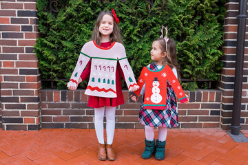 Funny girls with cardboard ugly Christmas sweaters. Holiday zero waste crafts with children. Kids recycle the boxes into funny creative xmas, diy concept