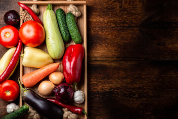 Various vegetables - zucchini, eggplant, pepper, tomato on a dark wooden background. Preparation for cooking. Place for your text.